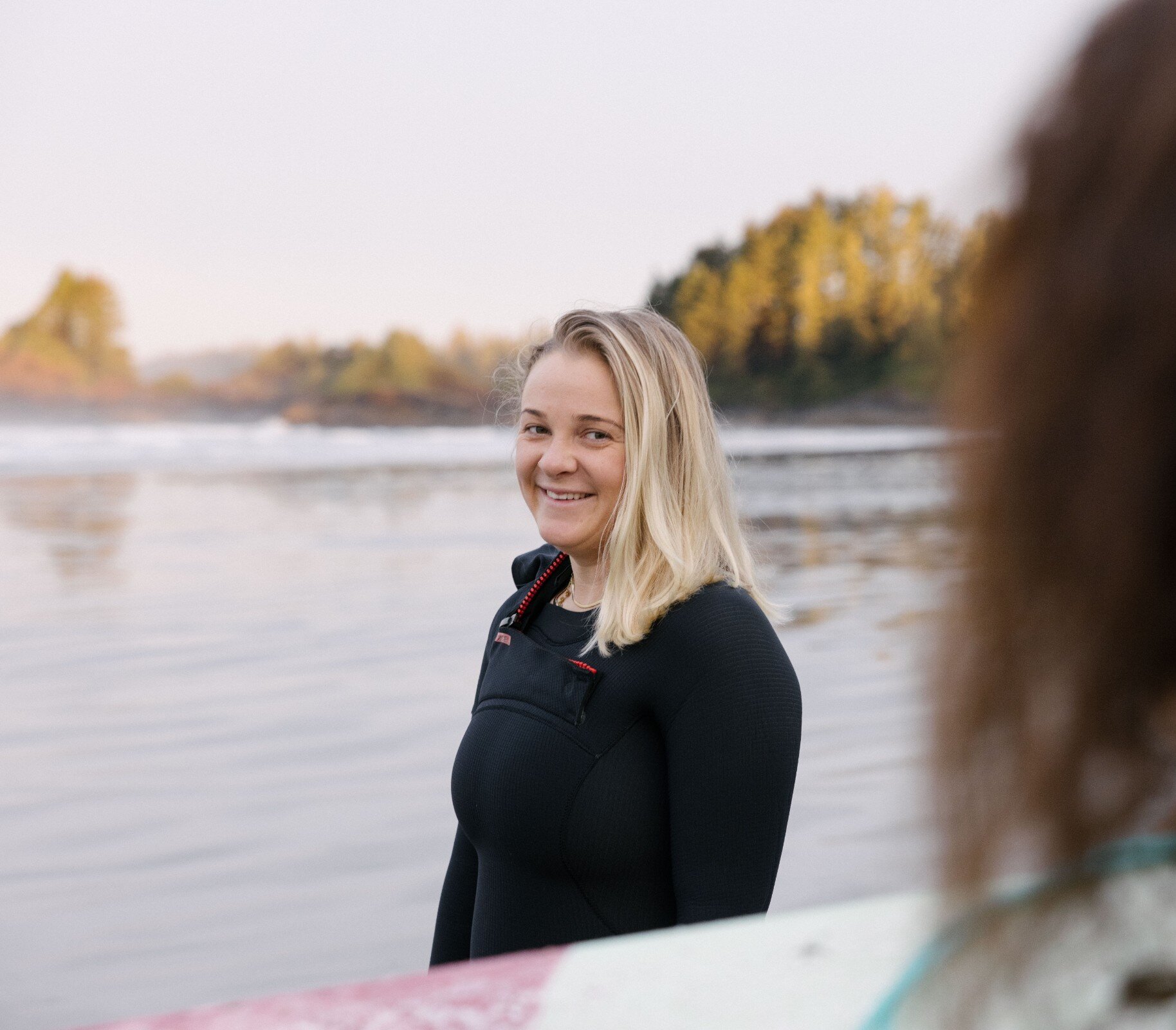 Person smiling in a wetsuit on the beach