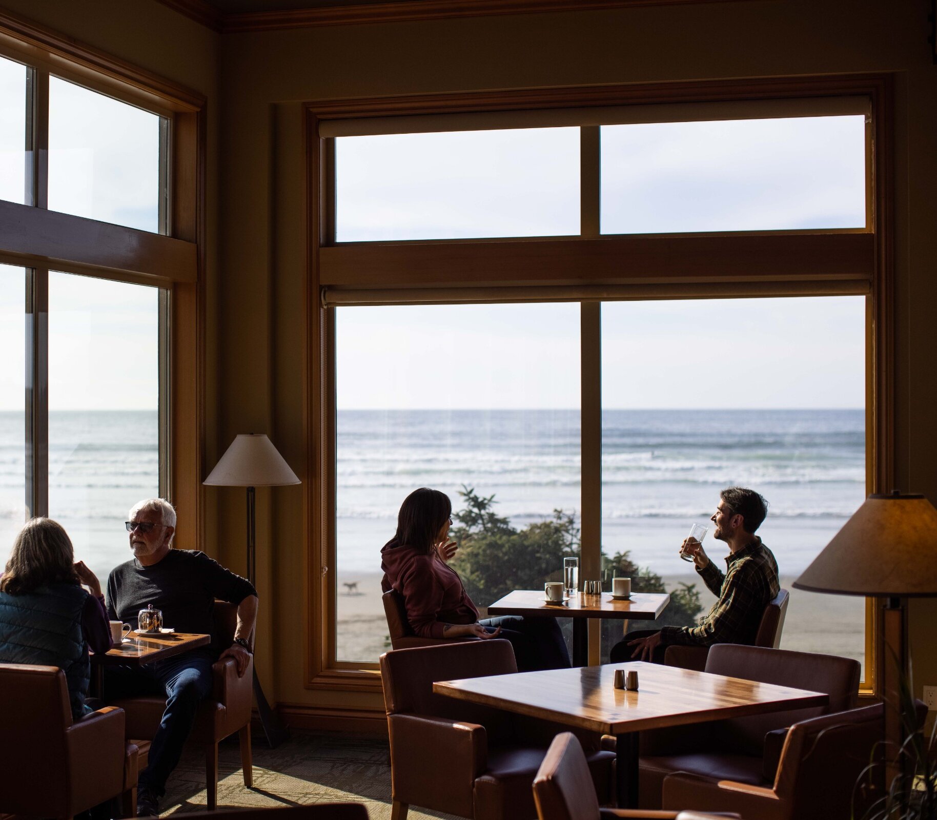 Interior of people having coffee in a restaurant looking out to the beach through the windows