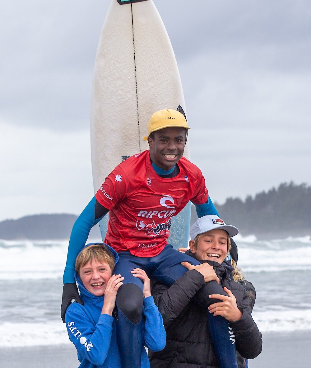 Teenager being held on the shoulders of his friends at a surf competition
