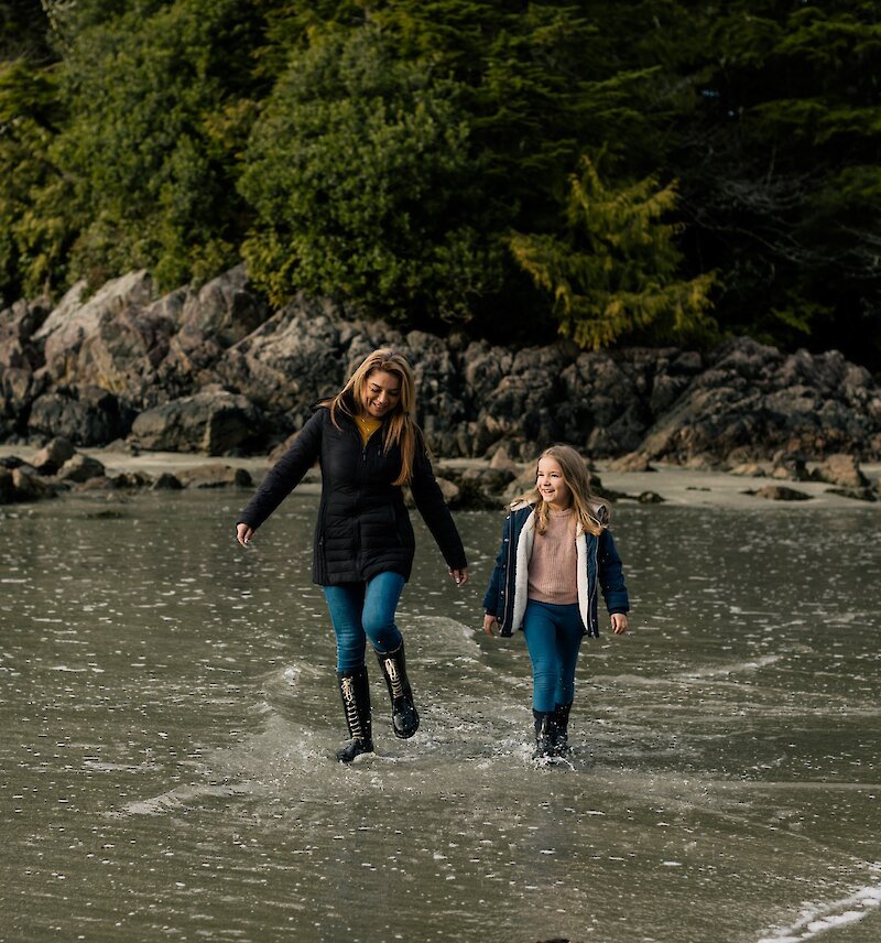 Mother and child walking along the beach, splashing in the surf