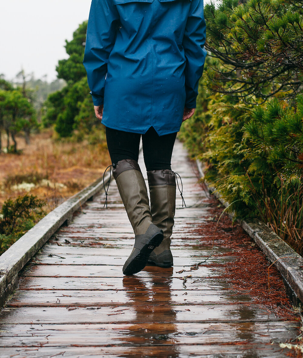 Person walking in gumboots on a boardwalk