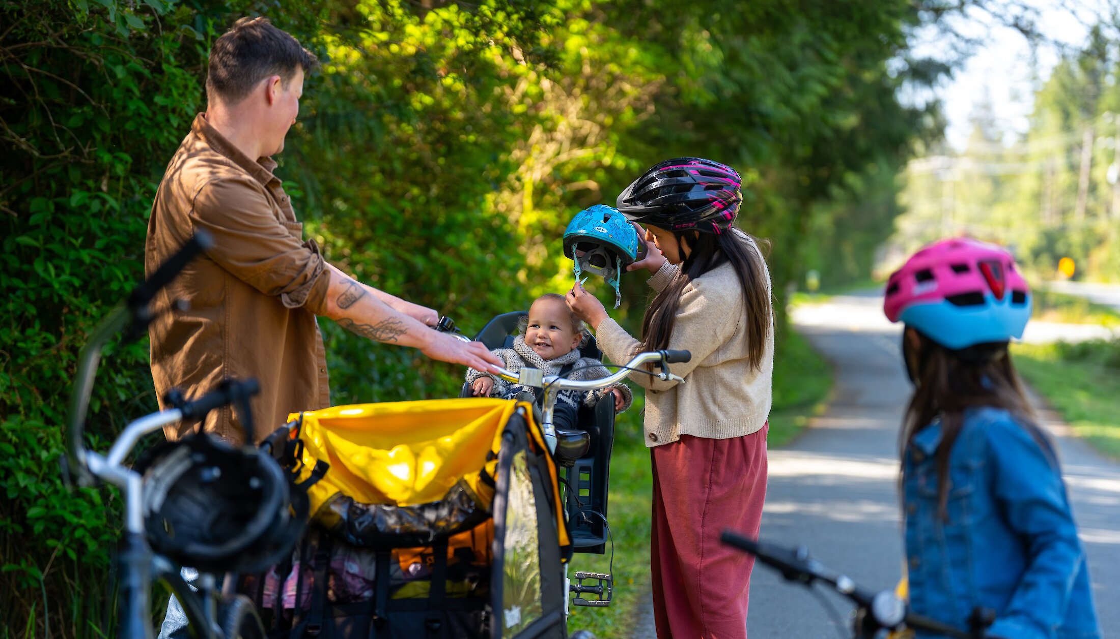 Family stopping to adjust their helmets on a bike path