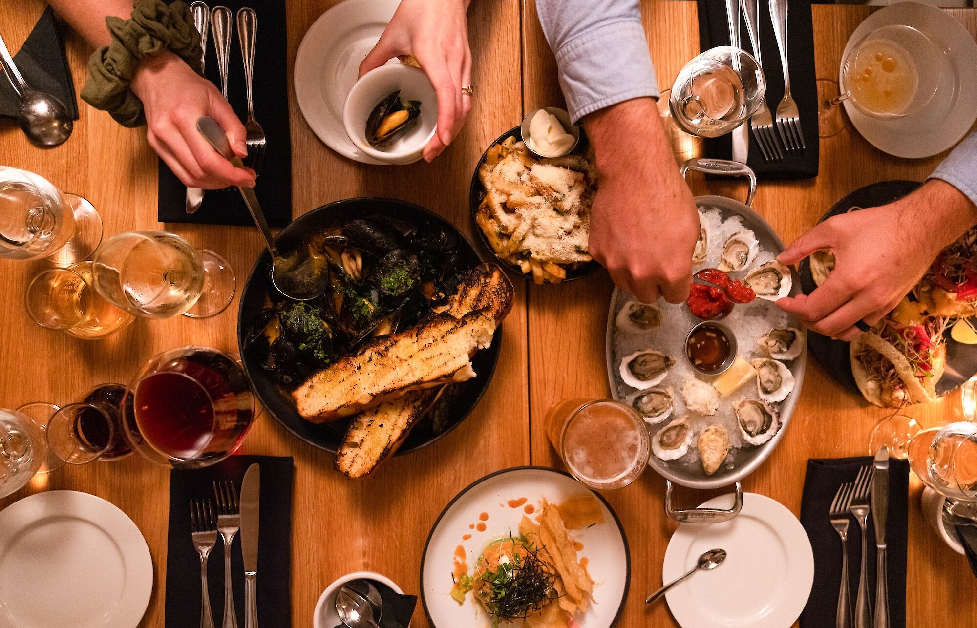 aerial shot of table with amny plates of food and hands
