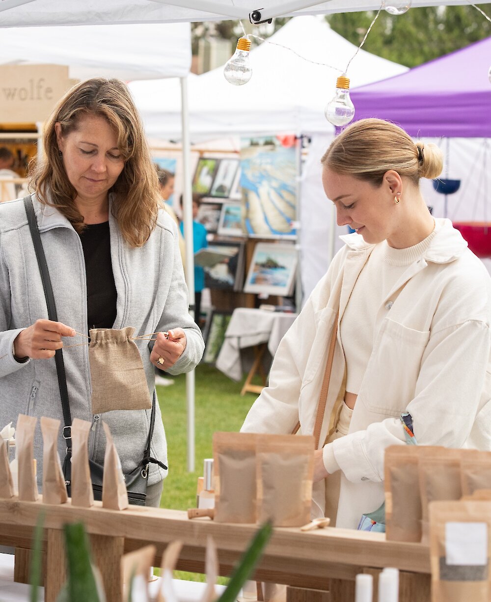 Two women looking at products at the Tofino Market