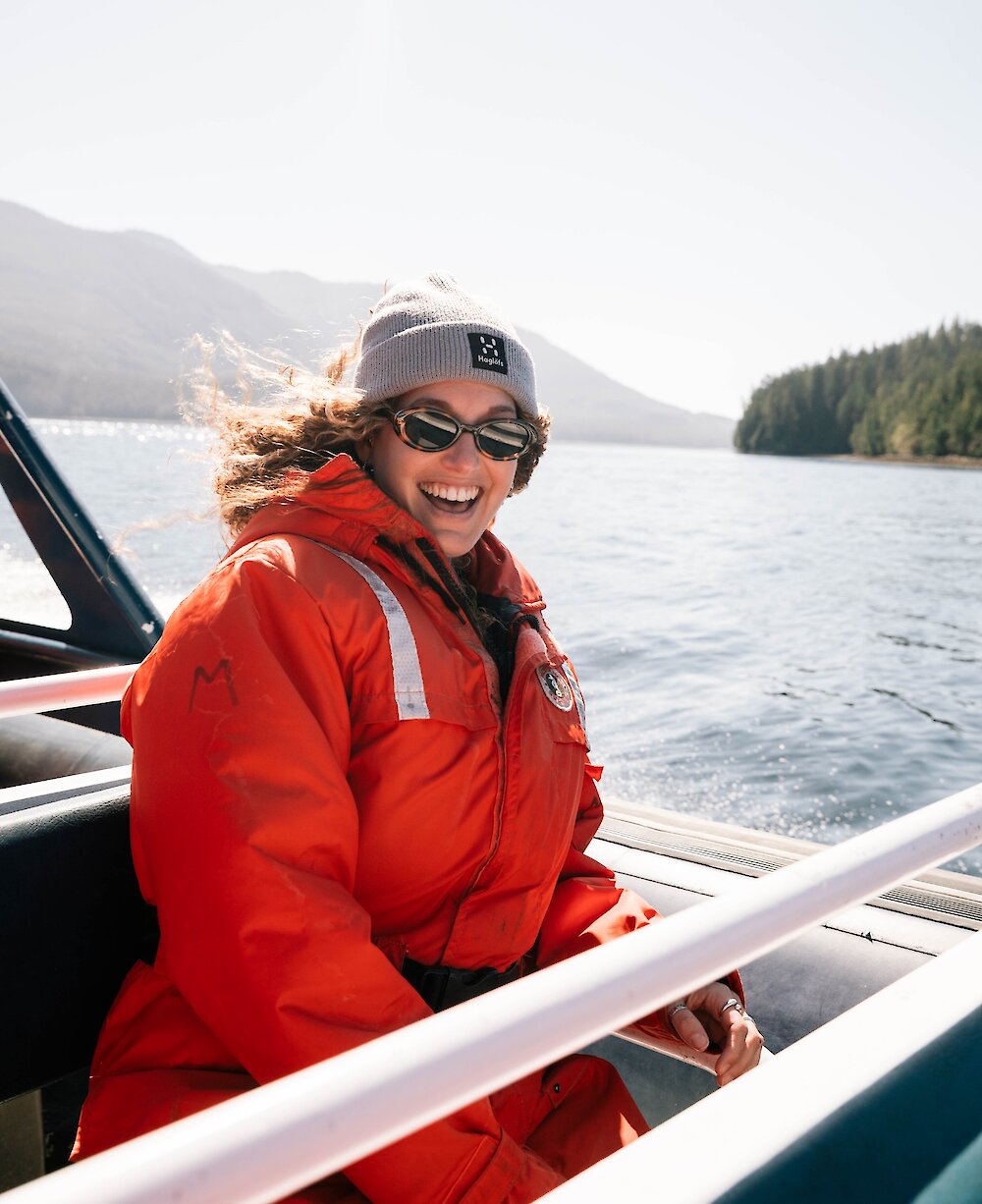 Woman in sunglasses and red floater suit on zodiac boat