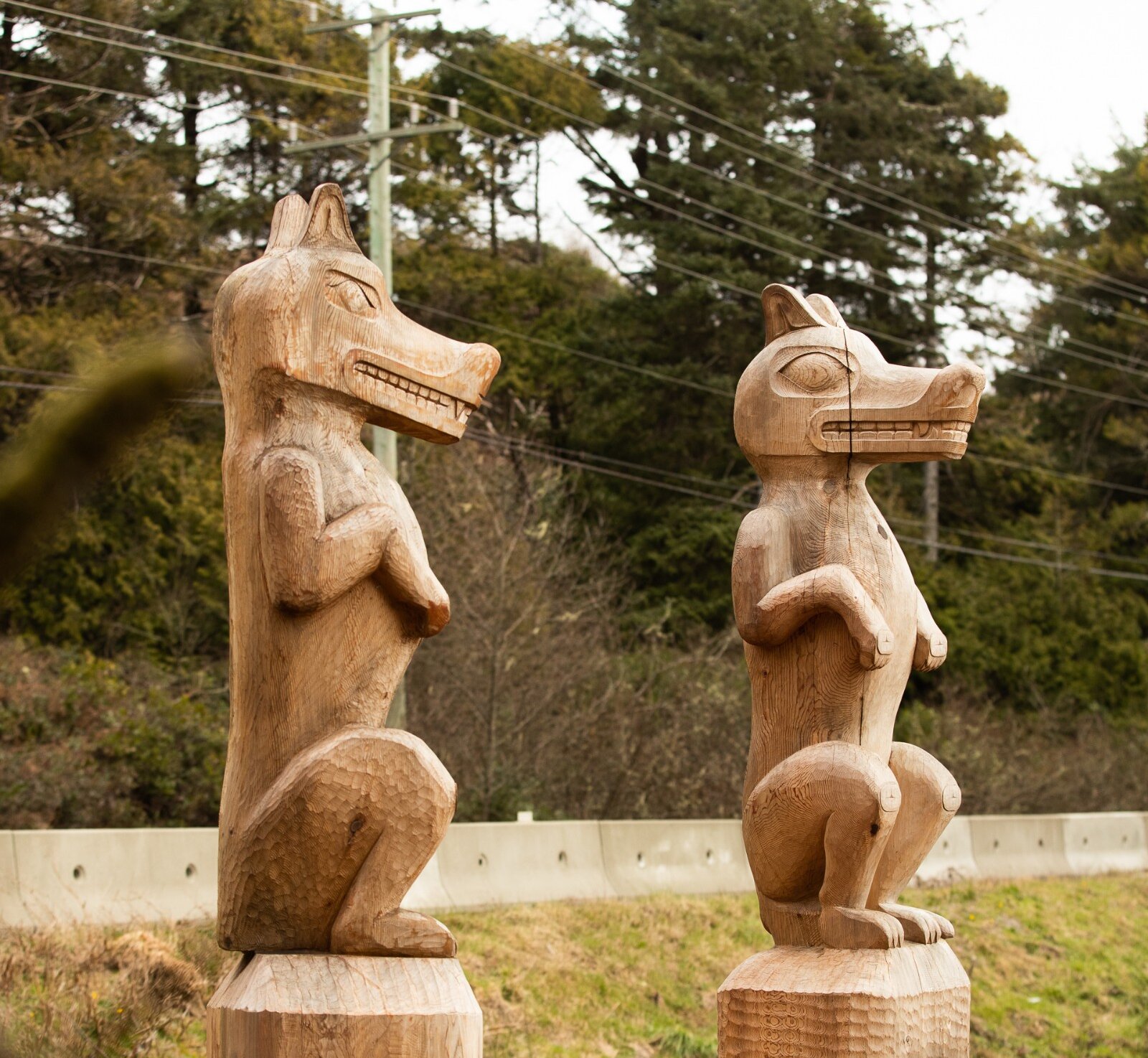 Two totem poles side-by-side along the multi-use pathway