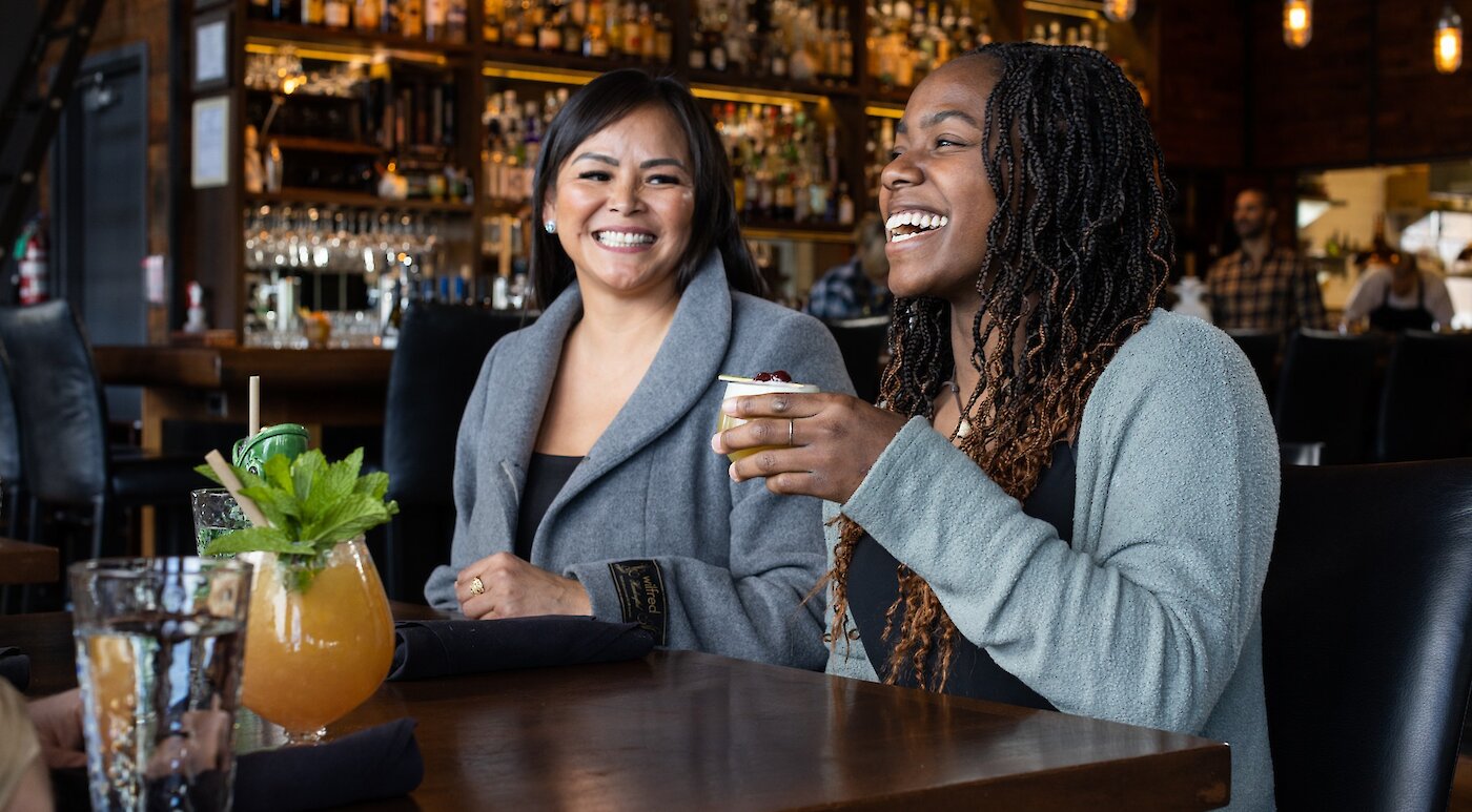 Indigenous woman and BIPOC woman enjoying a cocktail at a restaurant