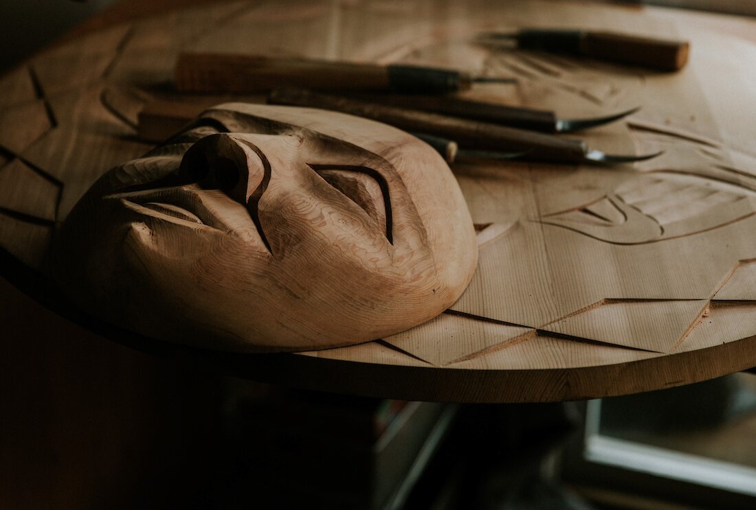 Mask carving with tools in the background