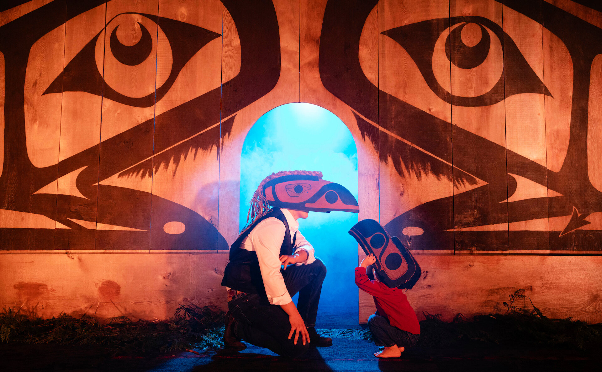 Person and child wearing Nuu-chah-nulth masks in a performance