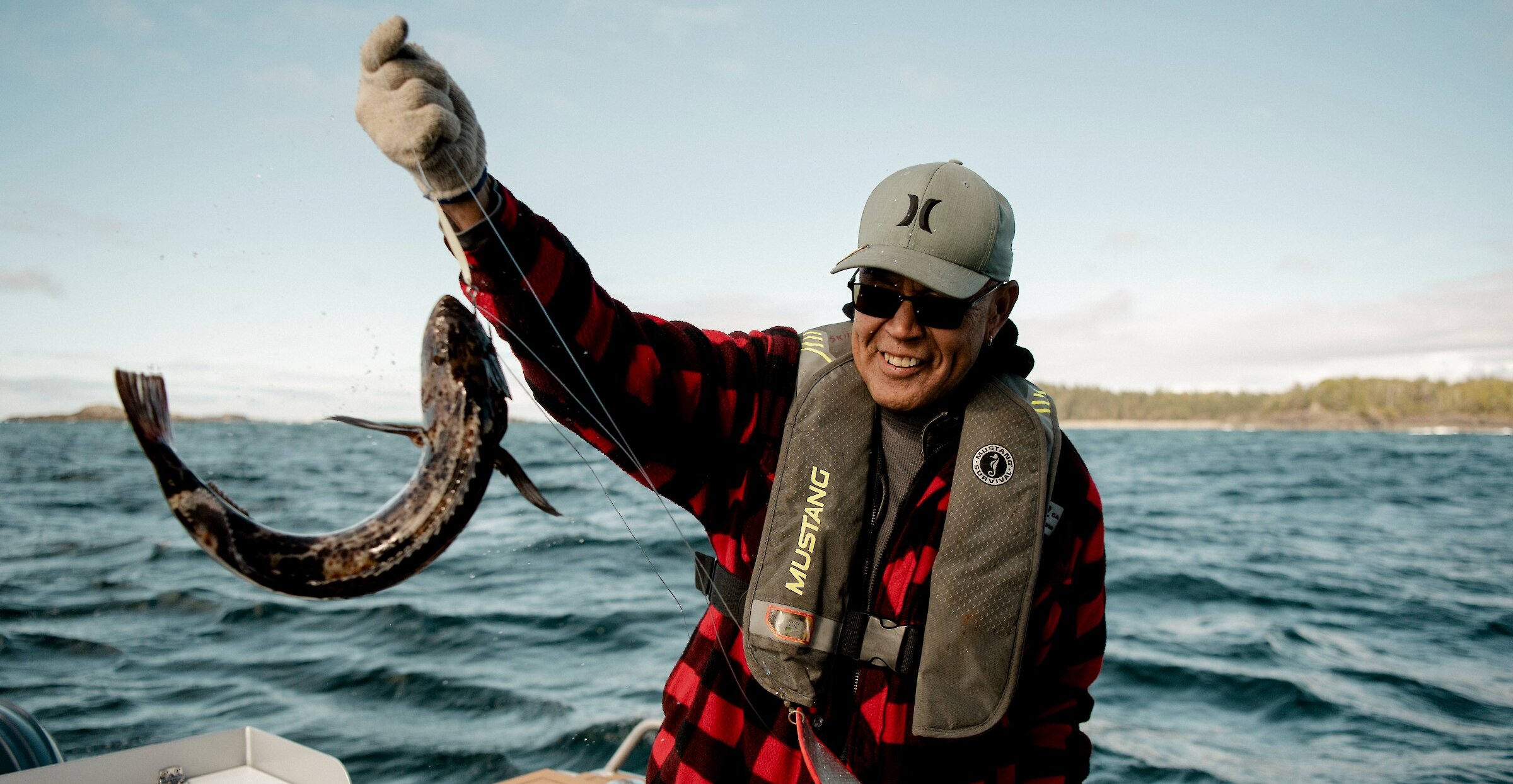 Person smiling holding up a lingcod on their line