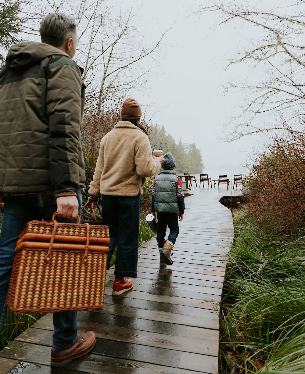 Family walking on a boardwalk with a picnic basket