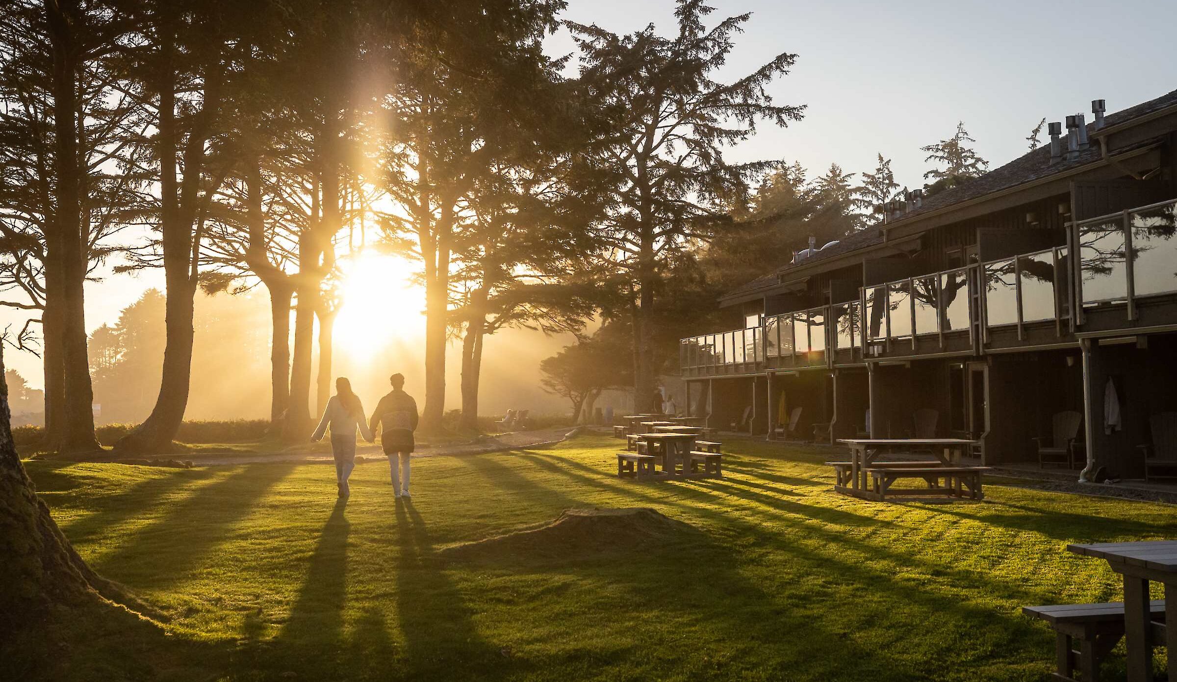 Two people walking in the sunset on the lawn of a beachside resort