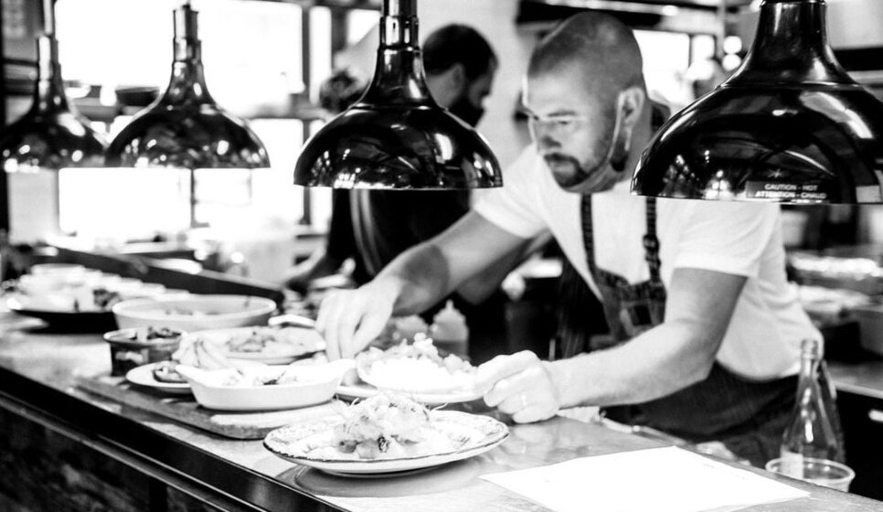 Chef Nick Nutting wearing an apron and at work plating dishes.