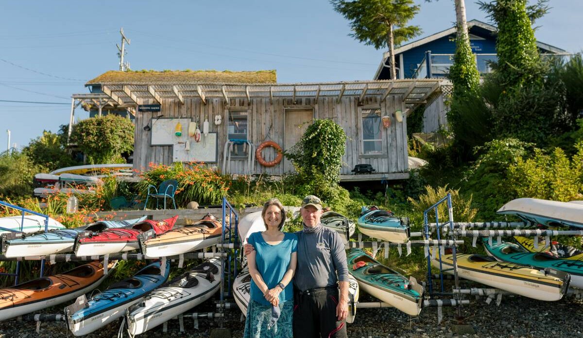 Natasha Baert and John Hockin in front of Tofino Sea Kayaking with kayaks in the sun