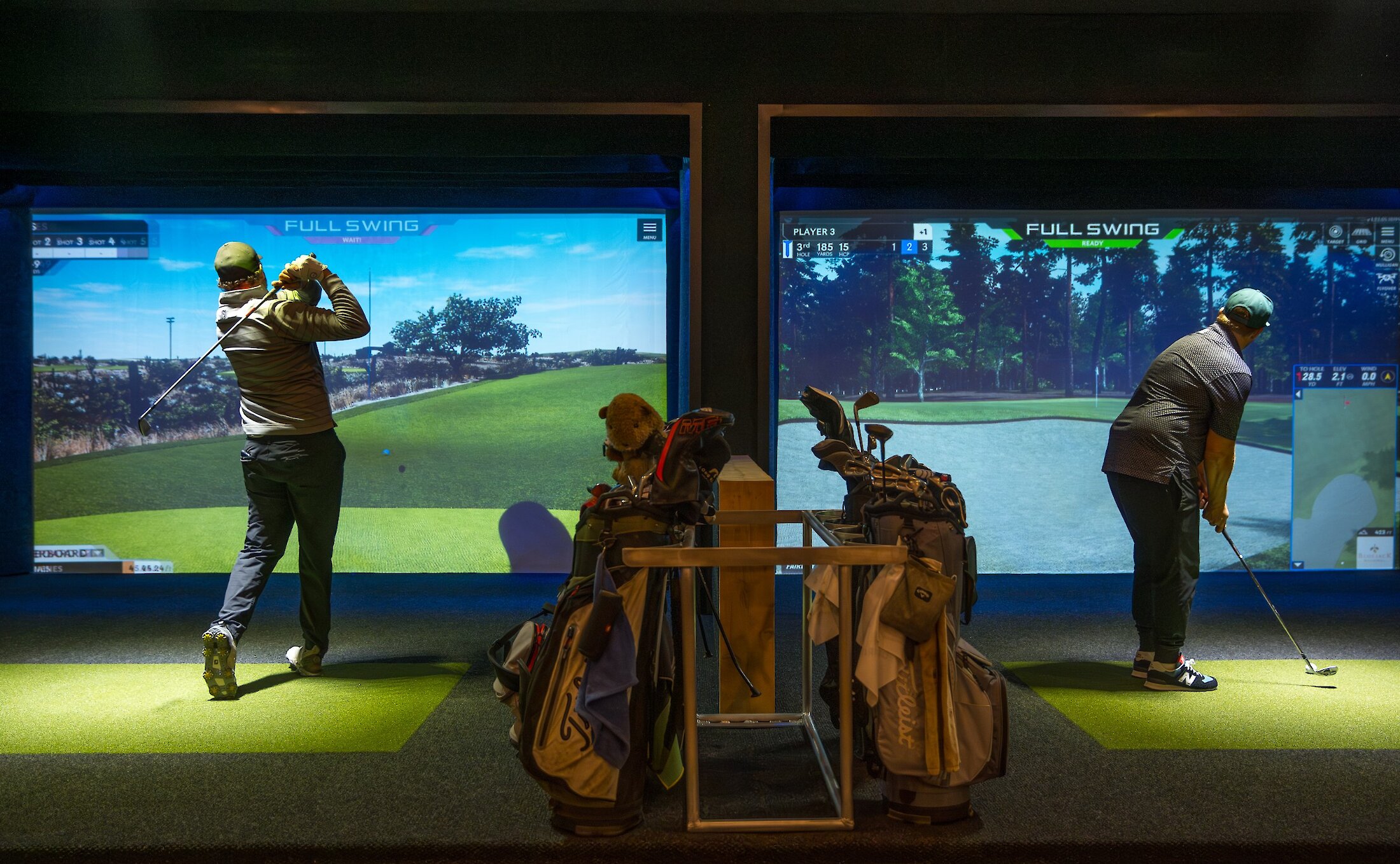 People golfing indoors in front of large screens at the "Pacific Sim" golf simulator.