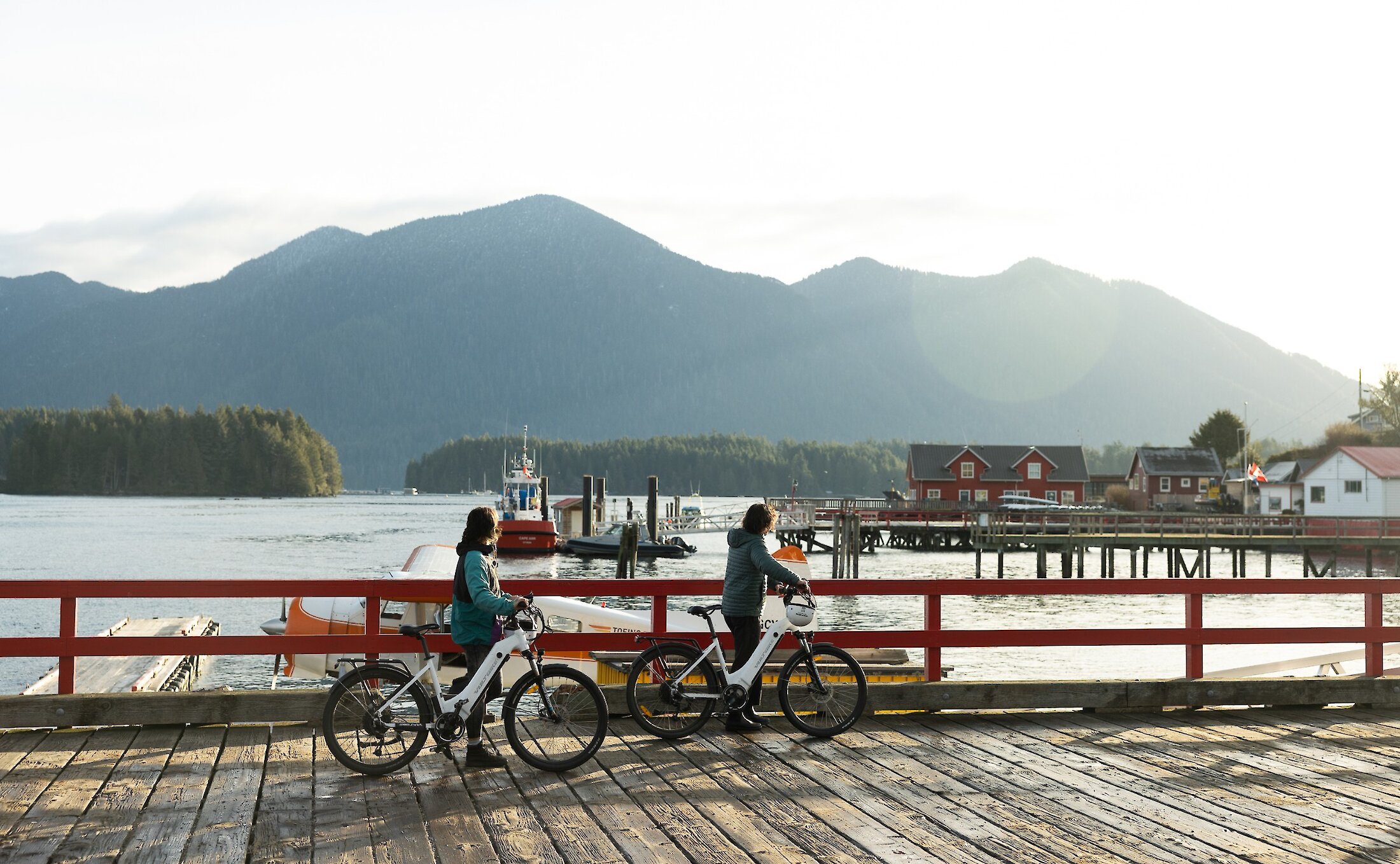 Two people walking their bicycles on the First Street Dock with Mount Colnett as a backdrop