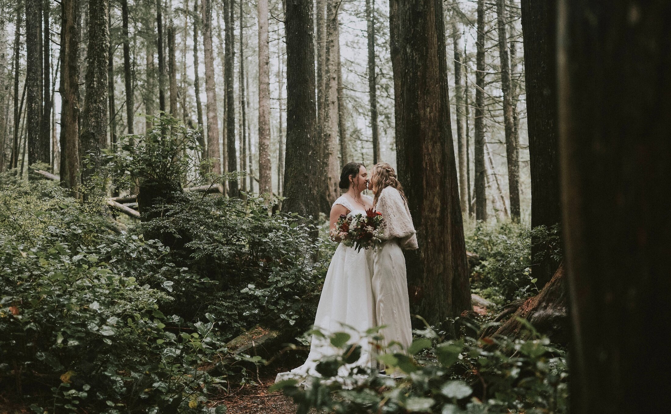 Same sex wedding couple kissing in the woods.