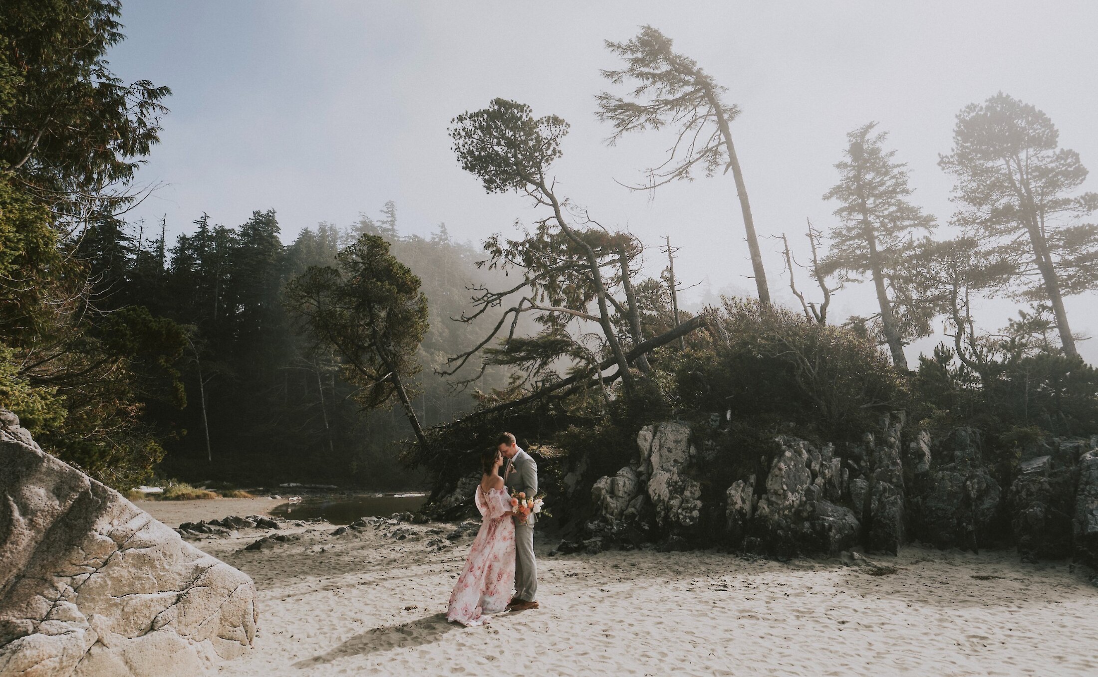 Wide shot of bride in pink dress and groom at Tonquin Beach