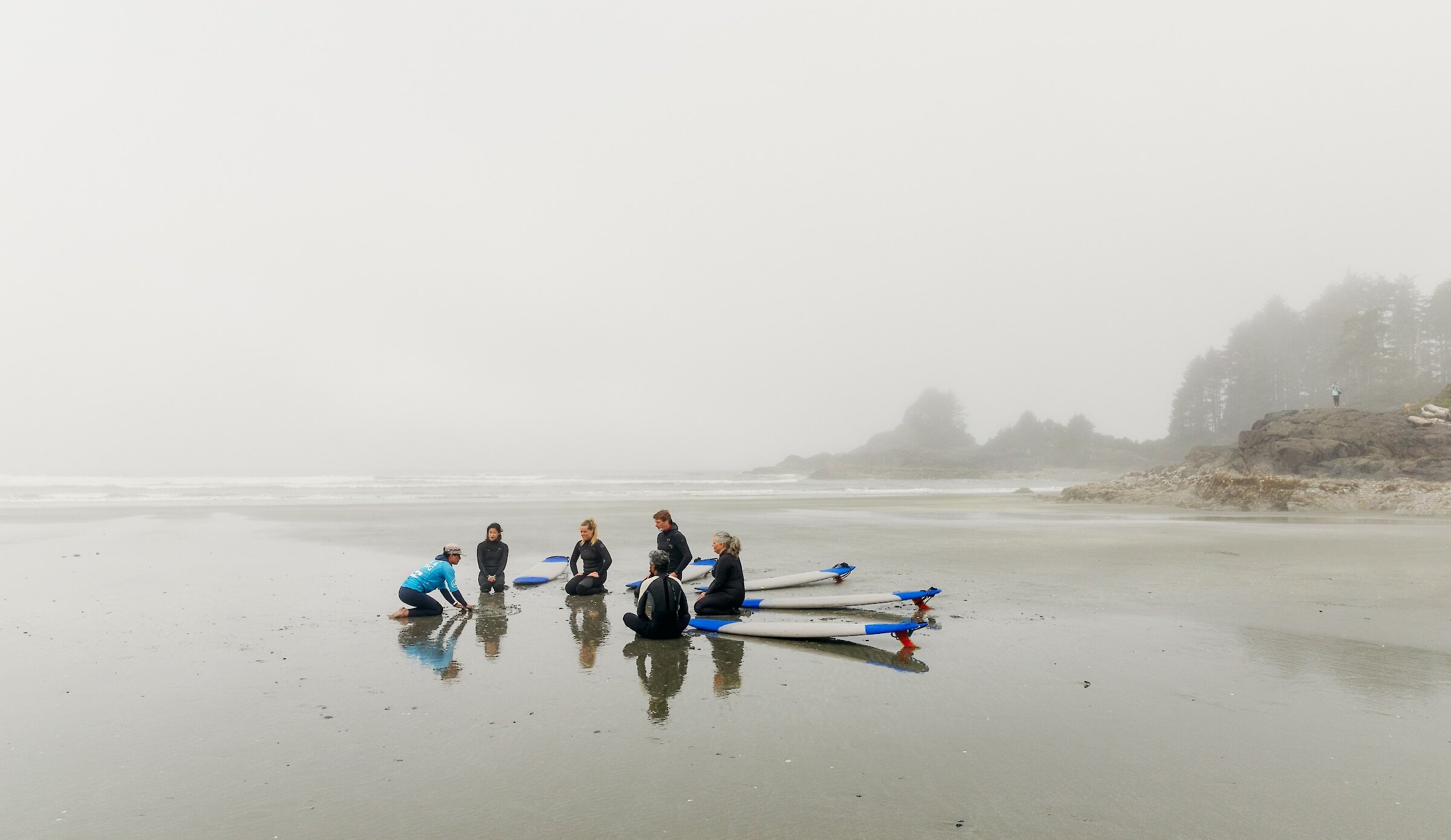 People learning to surf on a rainy beach