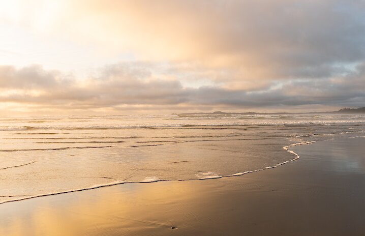 Sun and clouds reflecting in calm waters on the beach