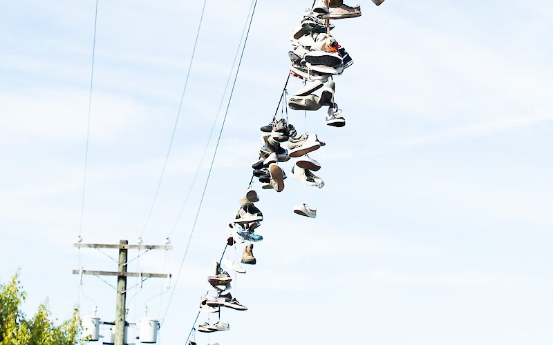 A wire hung with dozens of shoes below telephone wires.