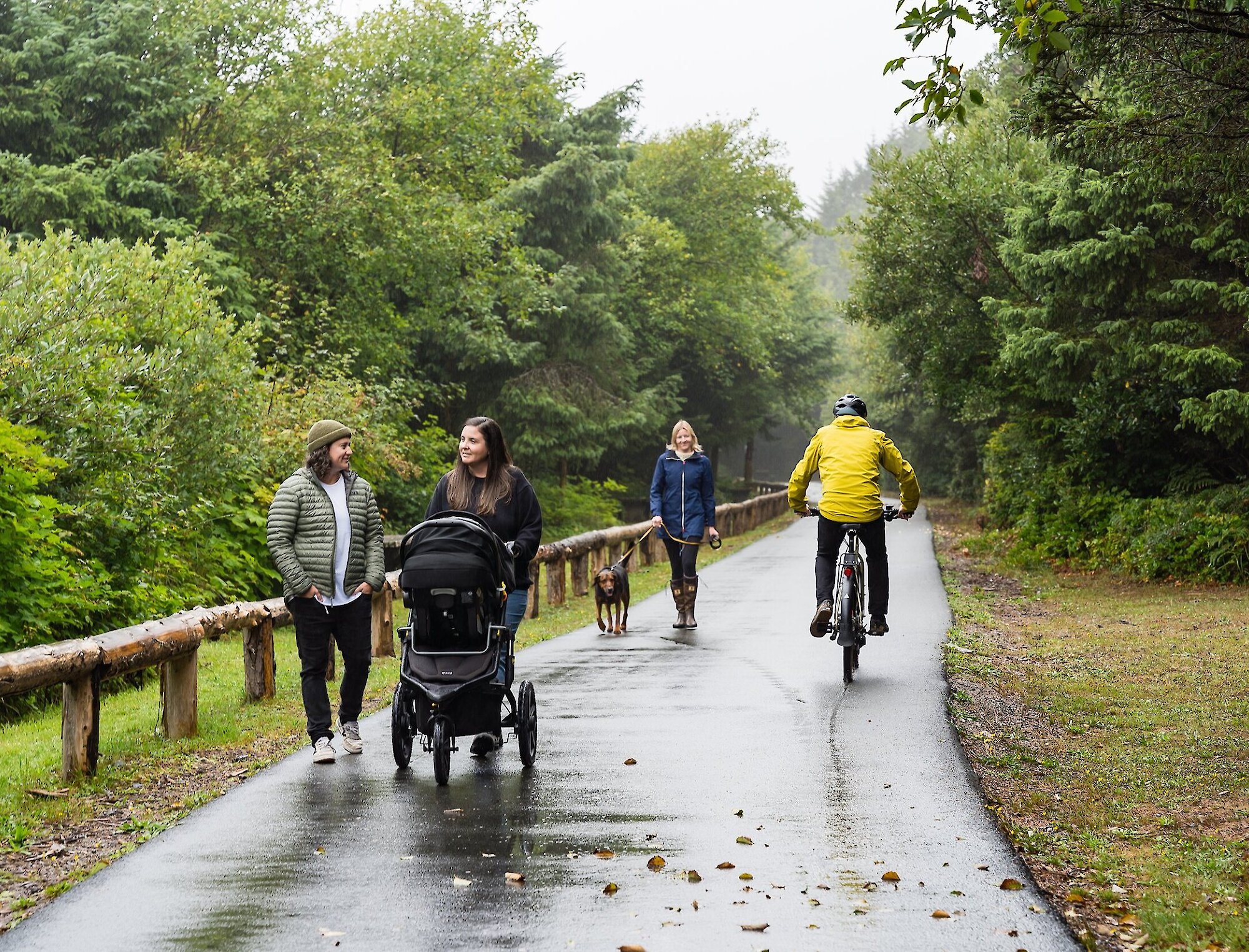 Person on a bicycle and woman with stroller using a paved pathway