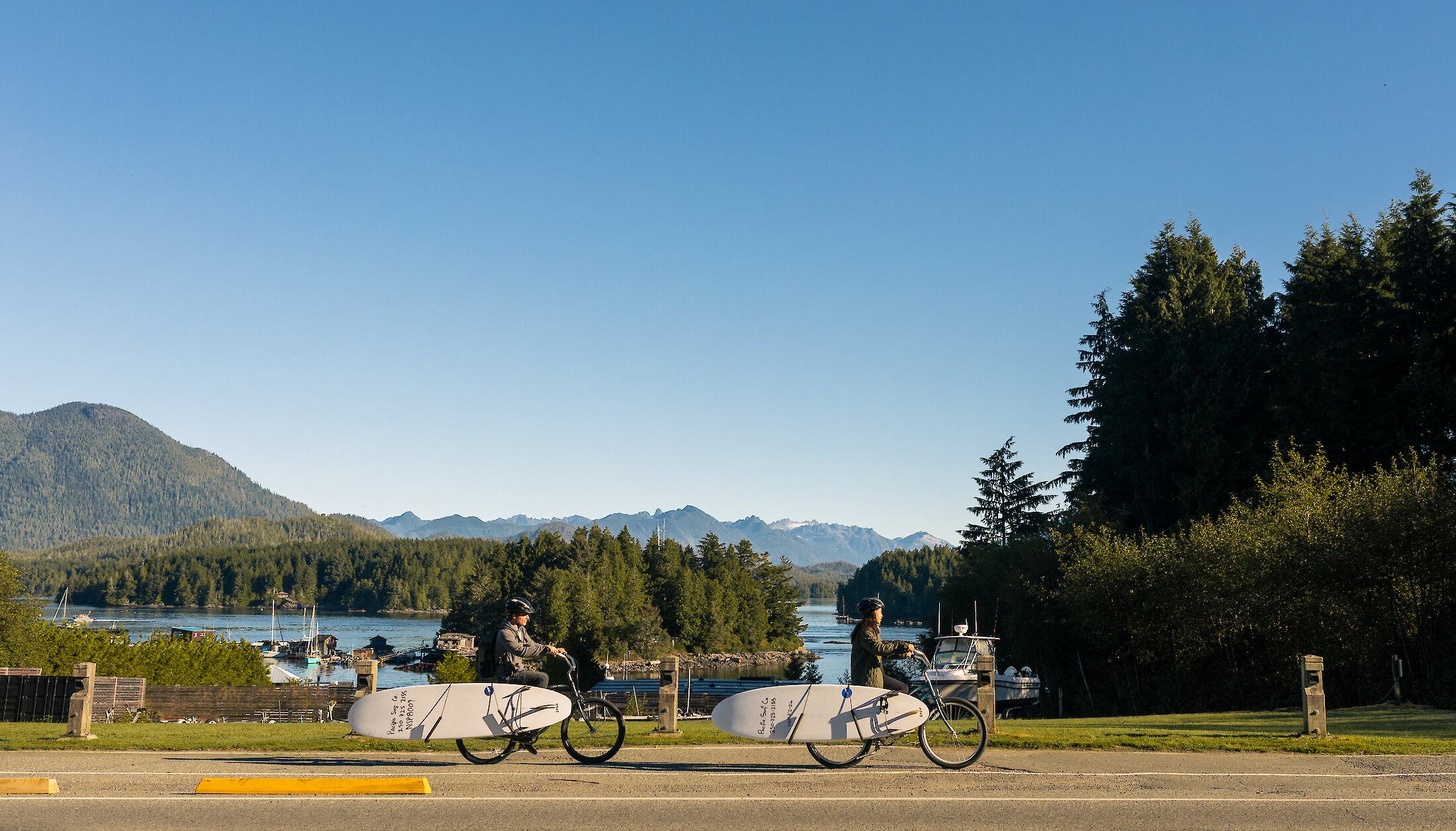 People biking with surfboards in town on their way to a surf lesson with Pacific Surf Co.