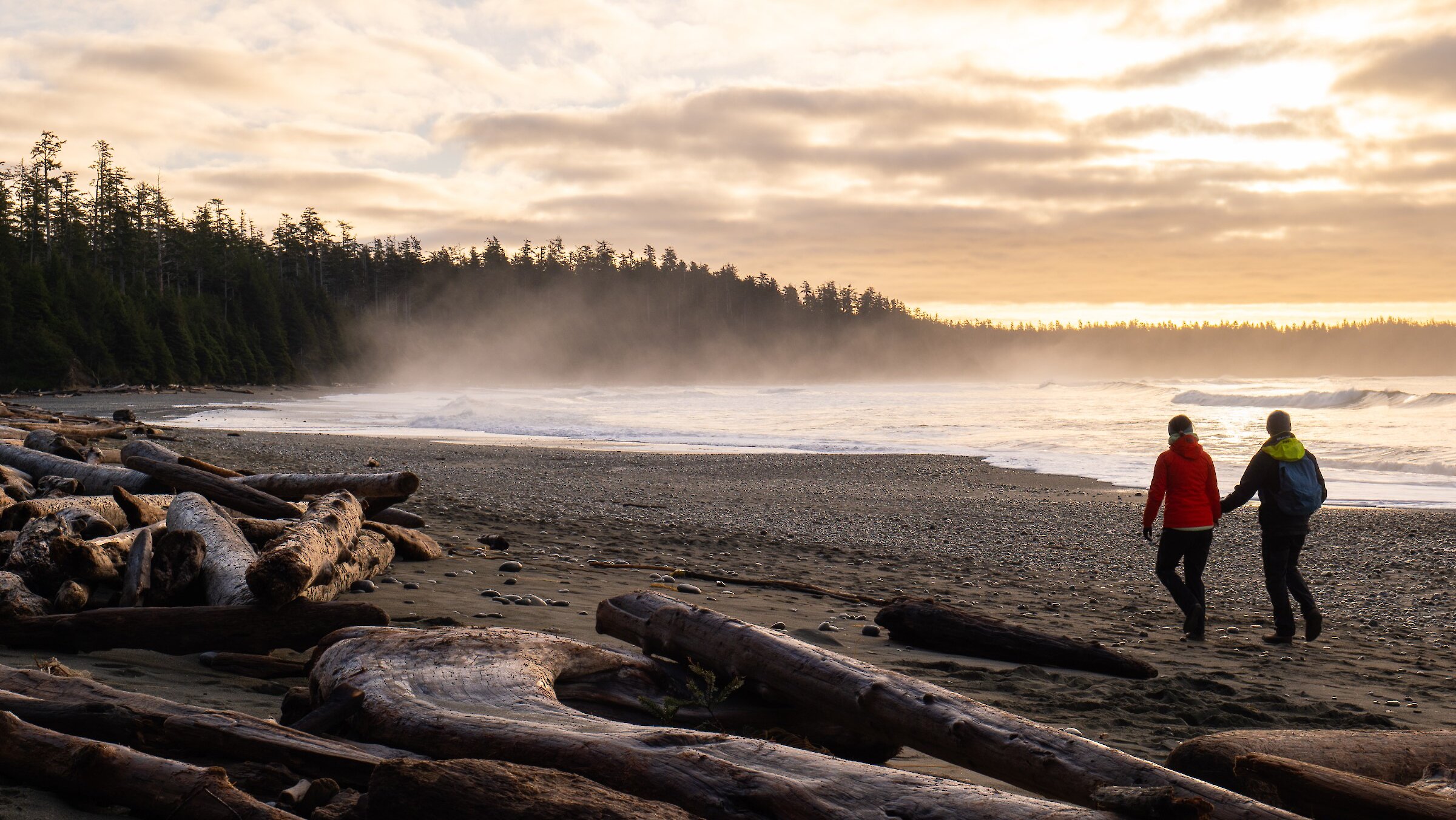 Silhouettes of two people walking at sunset toward view of Frank Island and North Chesterman Beach