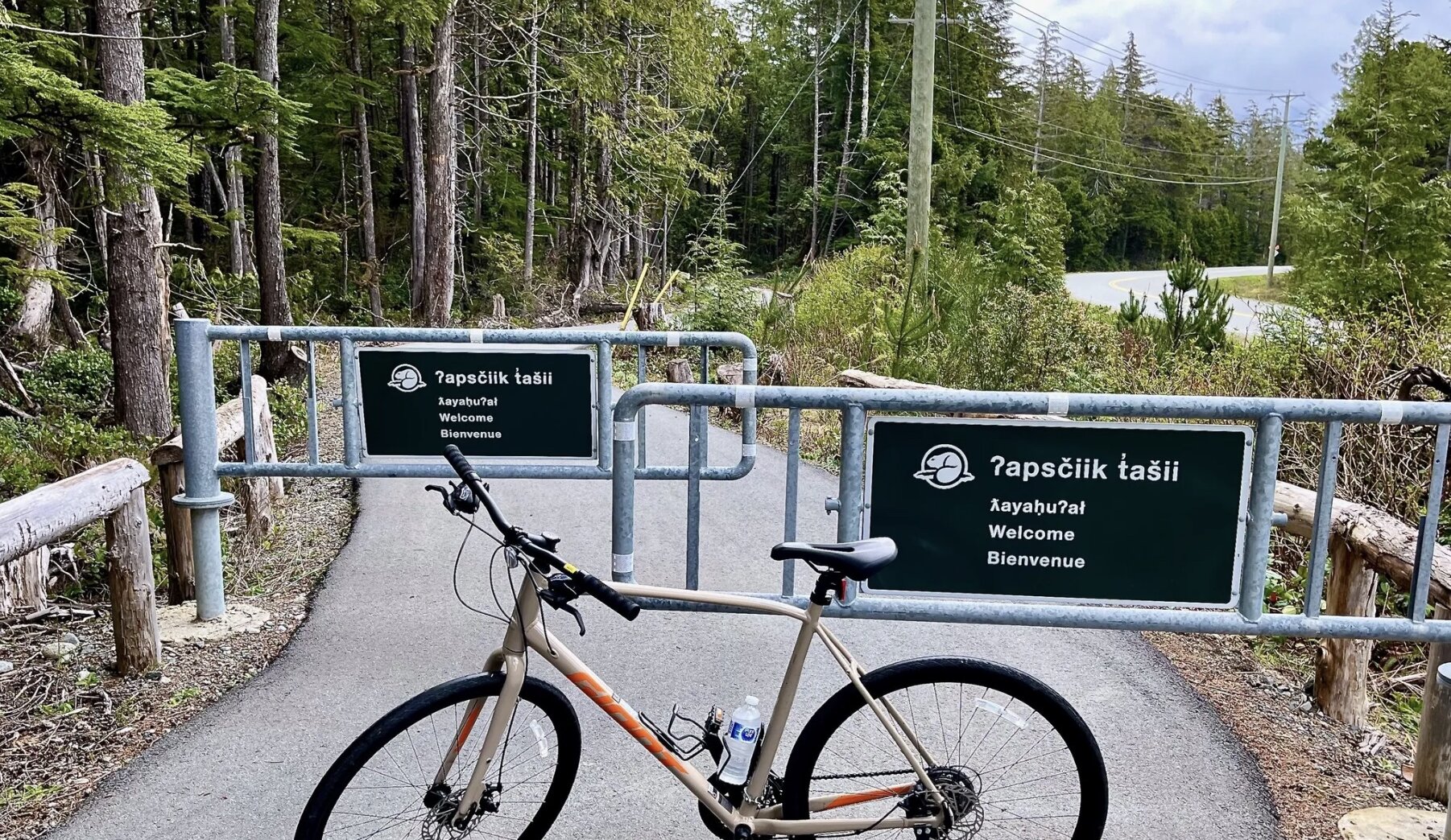 A pedal bike sitting in front of path gates in the Pacific Rim National Park Reserve that reads ʔapsčiik t̓ašii