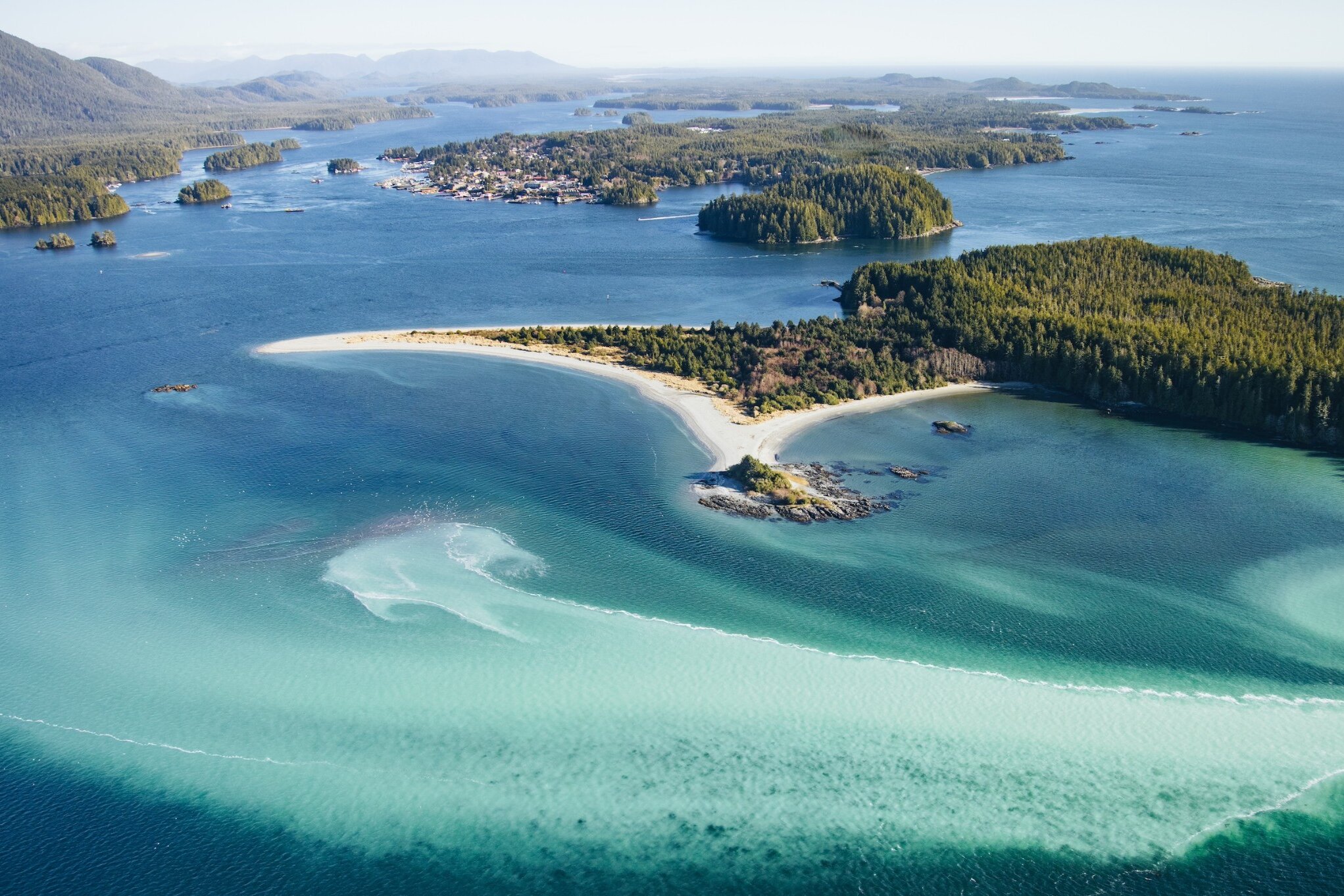 Aerial view of small forested islands, sandy beaches and the town in the distance