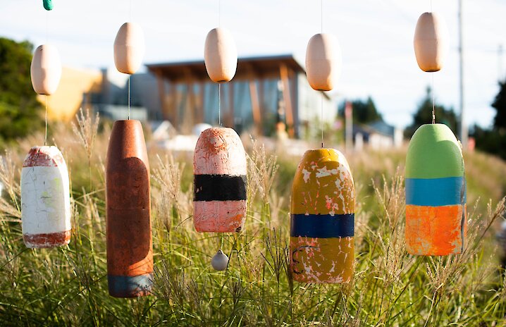 A public art display of repurposed colourful buoys strung from an arbor.