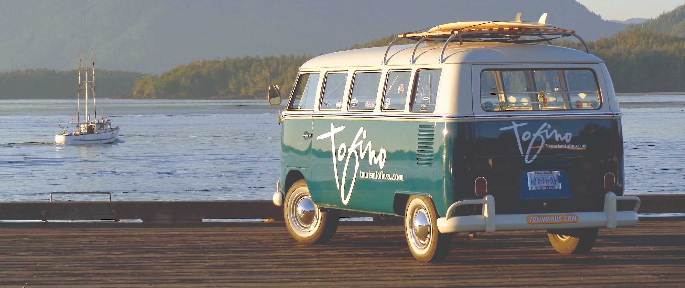 Tourism Tofino branded VW van parked on a doc with a surfboard on top