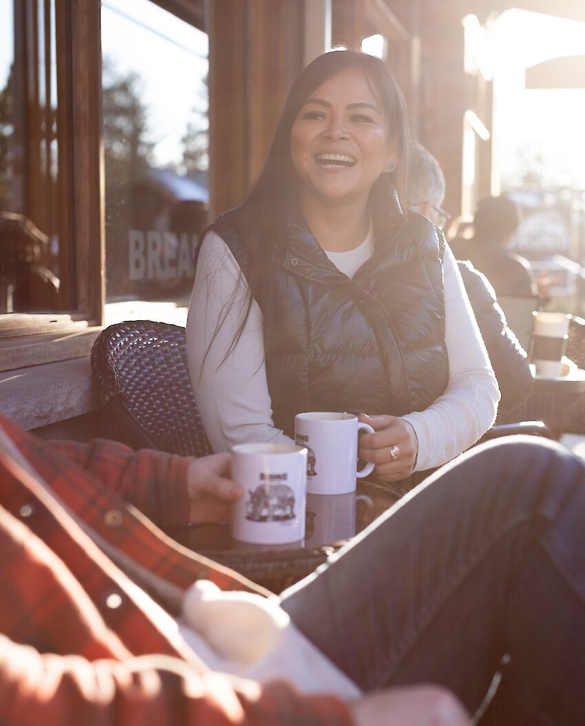 indigenous woman laughing and talking while holding a coffee mug