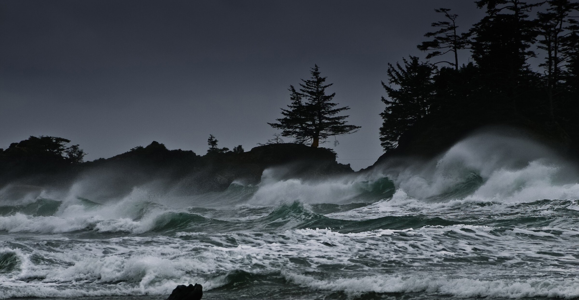 Stormy waves crashing on the beach with clouds in the background