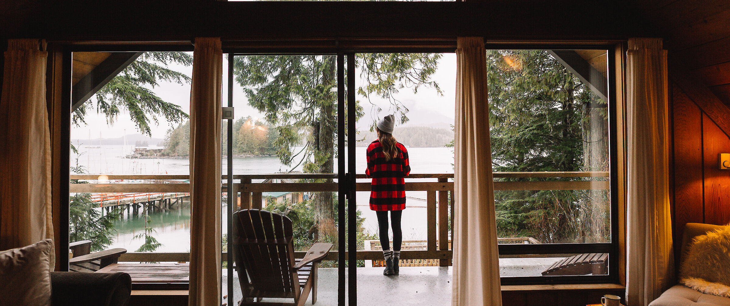 Person on the balcony looking out at a view of the ocean and a dock at the Shoreline Tofino