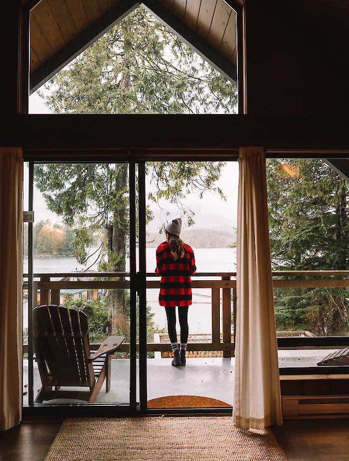 Person on the balcony looking out at a view of the ocean and a dock at the Shoreline Tofino