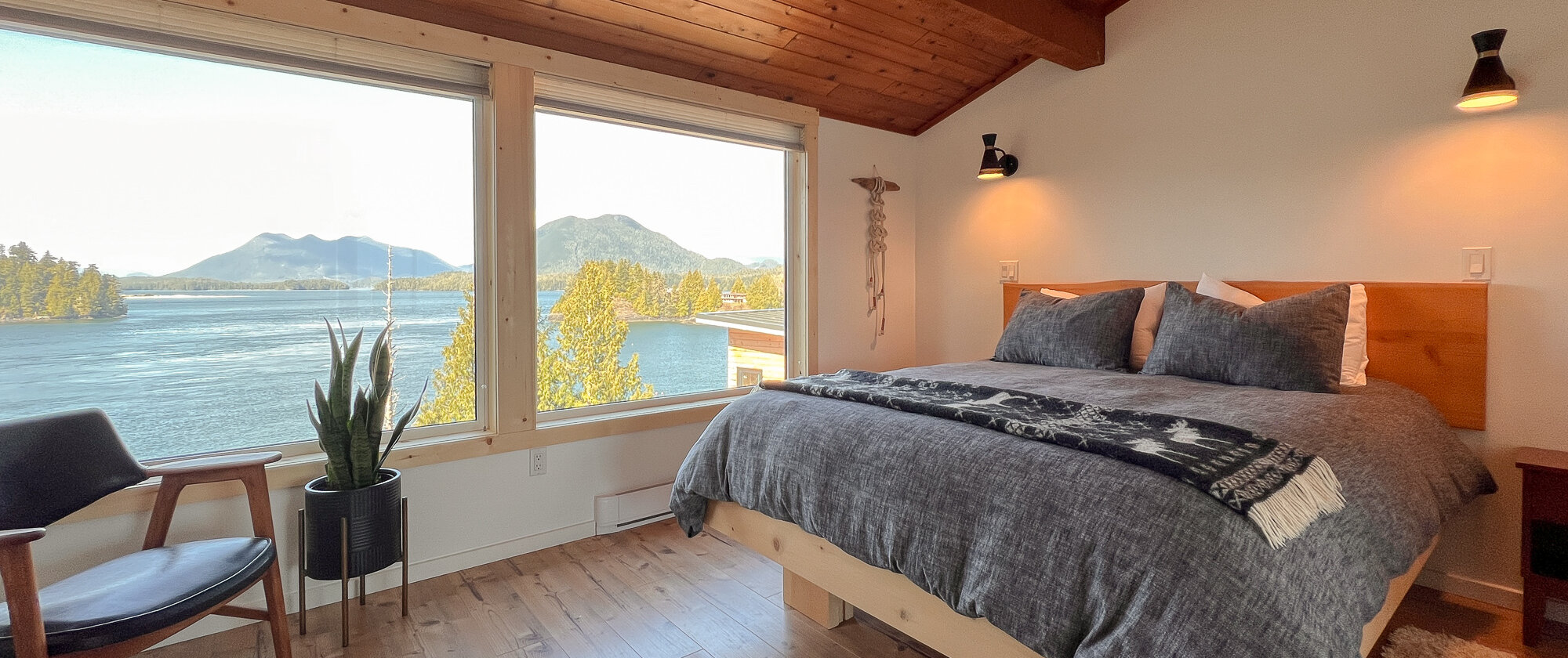 Interior shot of a bed, chair and beautiful ocean views out the window