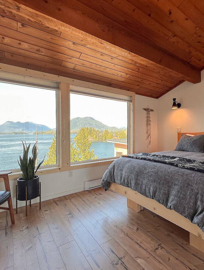 Interior shot of a bed, chair and beautiful ocean views out the window