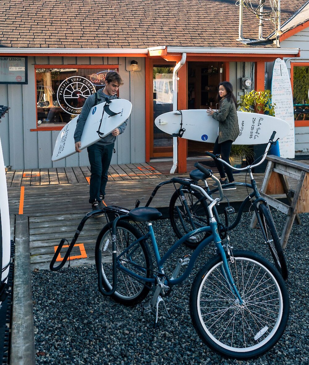 People picking up surfboards on their bikes for a surf lesson