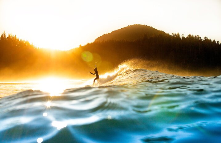 Sun glistening on the water with a surfer in the backgroun