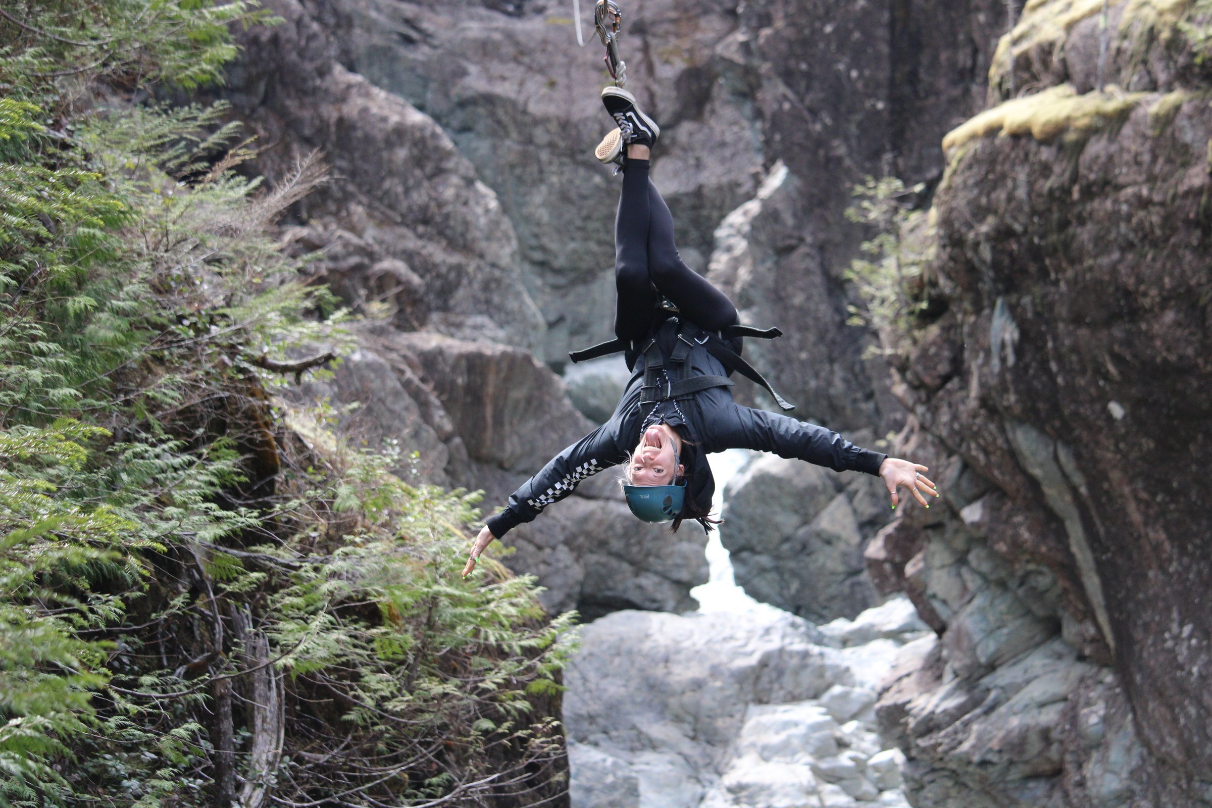 Ecstatic zipliner upside down in the canyon at West Coast Wild.