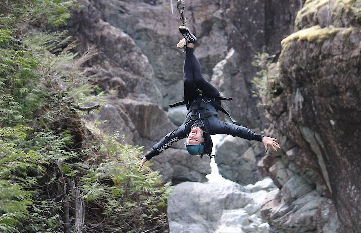 Ecstatic zipliner upside down in the canyon at West Coast Wild.