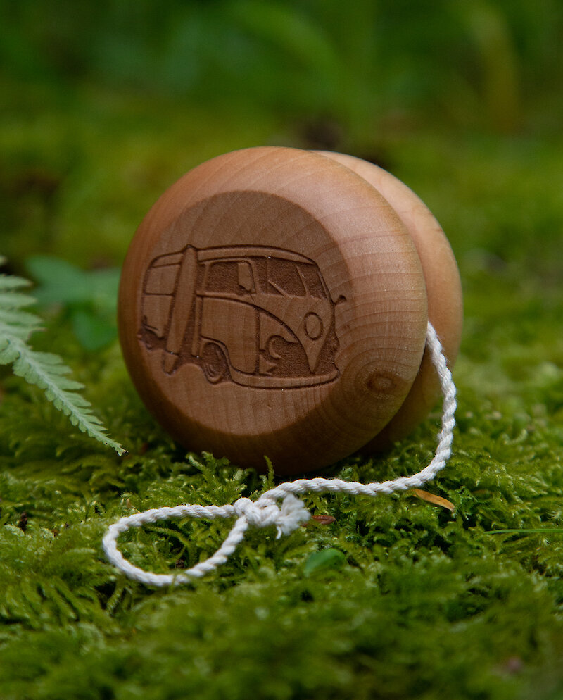 A wooden yo yo with a carved VW van on it