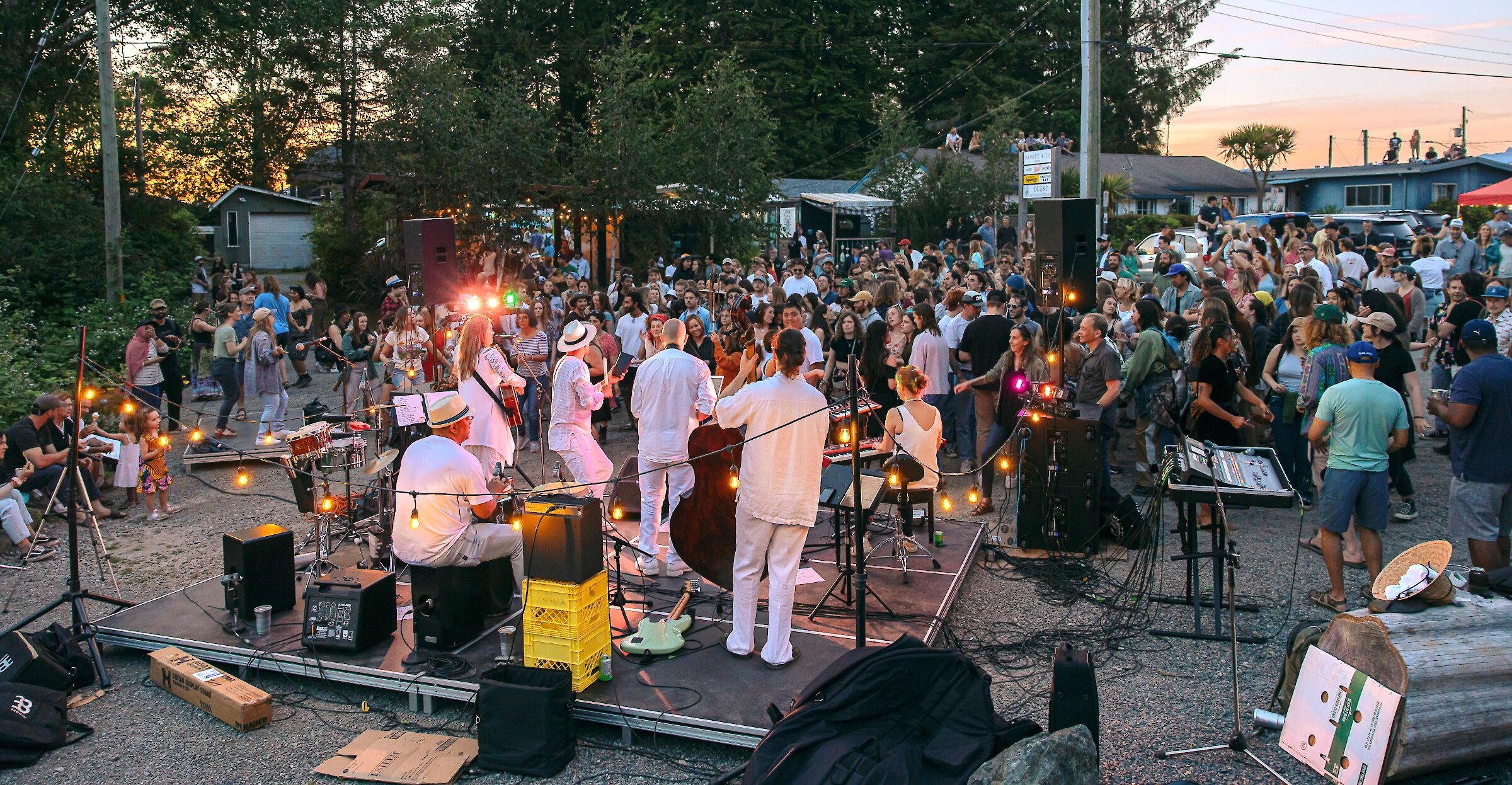 Large group gathering in front of a jazz band playing on an outdoor stage