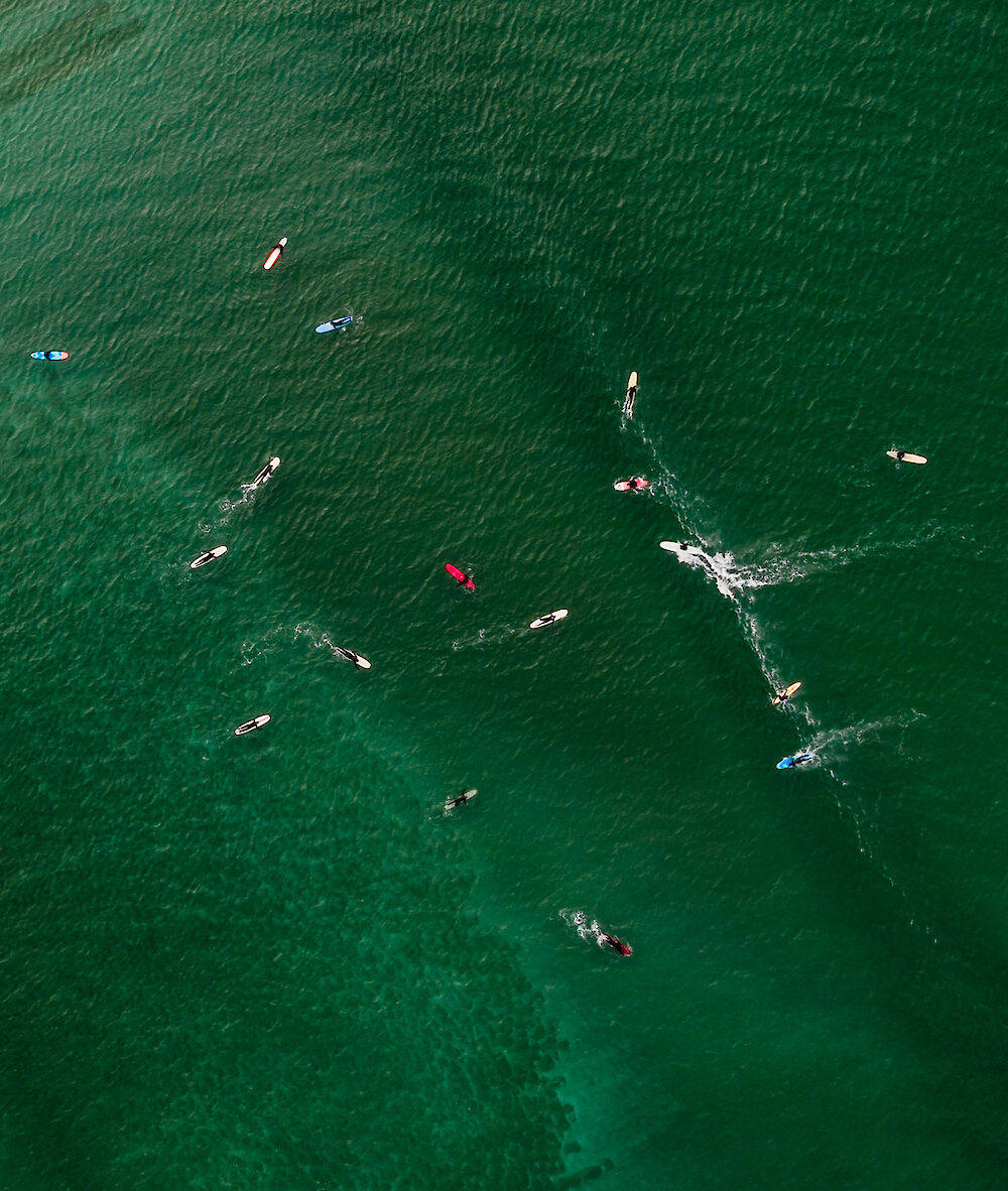 Looking down at surfers on their boards on the green ocean